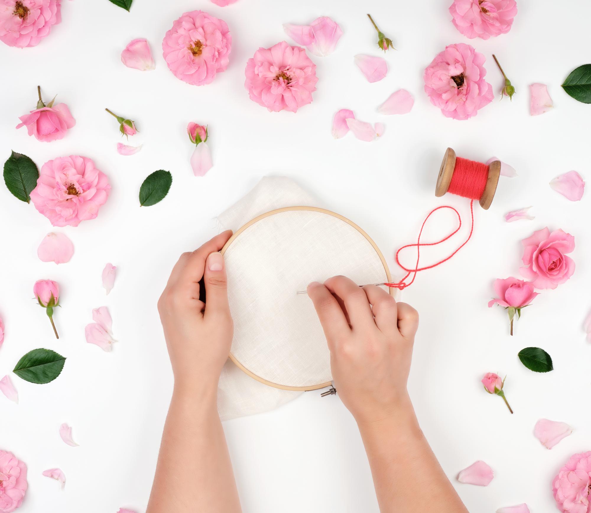Artist sewing floral embroidery on hoop